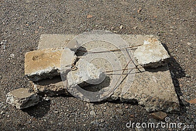 One old gray broken square plate with pieces of concrete and rusty iron fittings Stock Photo