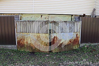 One old gray closed iron gate in brown rust and a fence Stock Photo