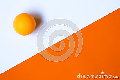 One orange ping pong ball on an orange and white background. Stock Photo