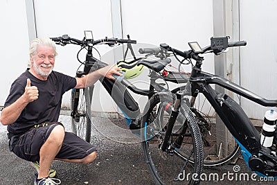 One people, senior man has finished washing the two bicycles and raises his thumb as a sign of victory Stock Photo