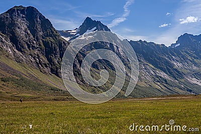 One person in the background hiking in the Norwegian valley with big mountains Stock Photo