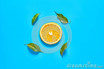 One piece of mandarin or orange and green leaves on blue background. Fruit purchasing concept. Top view Stock Photo