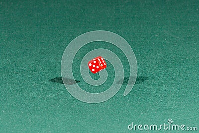 One red dice falling on a green table Stock Photo