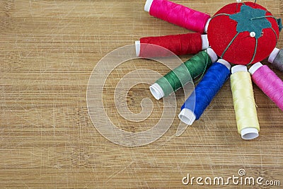 One red pincushion and several colourful threads as a sun Stock Photo