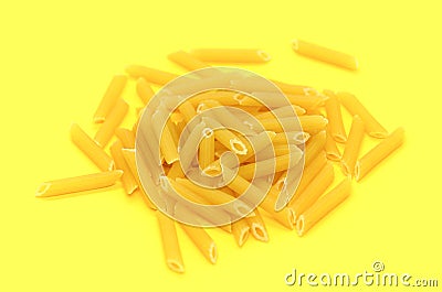 One serving of raw Penne pasta on yellow background. Classic extruded type of pasta Stock Photo