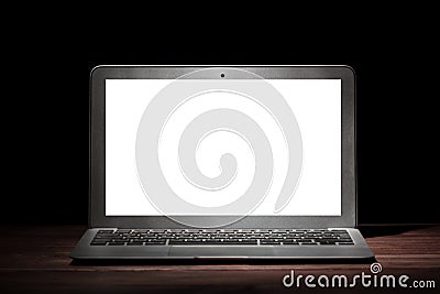 One silver modern laptop with empty white screen on wooden table in a dark room on black background. Nice mockup for your IT Editorial Stock Photo