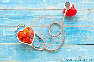 One single alone red heart love shape hand exercise ball with bandage MD medical doctor physician`s stethoscope blue wood backgrou Stock Photo