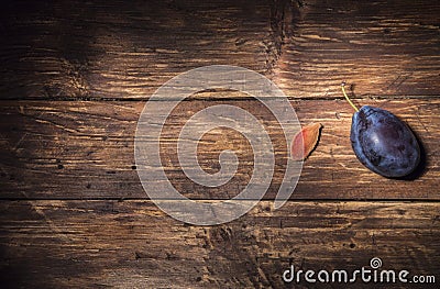 One single plum and a plum stone on a dark wooden board. Fruit background. Text space. Top view. Agriculture, Gardening, Harvest Stock Photo