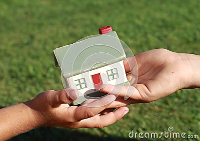 One small kids hand giving a model of a house Stock Photo