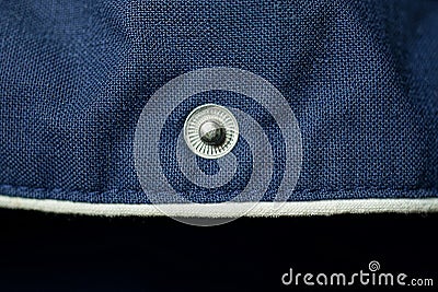 One small metal button rivet on blue fabric Stock Photo
