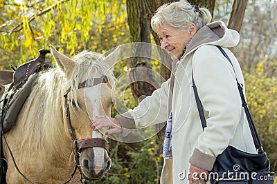 Portrait of a smiling old lady with a horse. Stock Photo