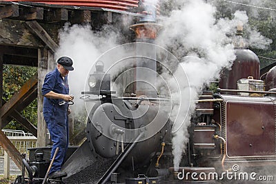 One staff is cleaning the ash from smokebox of the steam Locomotive Editorial Stock Photo