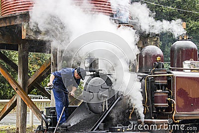 One staff is cleaning the ash from smokebox of the steam Locomotive Editorial Stock Photo