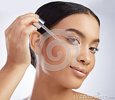 One step away from the smoothest skin of your life. Studio shot of an attractive young woman using a serum on her face Stock Photo