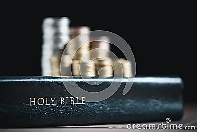 One tenth or tithe is basis on which Bible teaches us to give one tenth of first fruit to God. coins with Holy Bible. Biblical Stock Photo