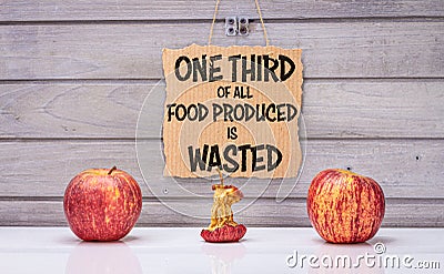 One third of all food is wasted text, 3 apples, one rotten to illustrate estimated global food waste Stock Photo