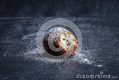 A single traditional Dutch oliebol (dough fritter) on a textured black background horizontal Stock Photo