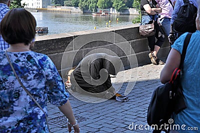 Begging for alms on the Charles Bridge in Prague. Editorial Stock Photo