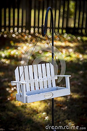 One white bird feeder hanging on a black pole Stock Photo