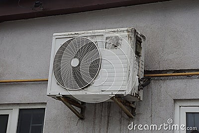 One white dirty air conditioning fan hanging on a gray wall Stock Photo