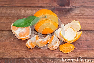 One whole and peeled mandarin orange on dark wooden surface Stock Photo