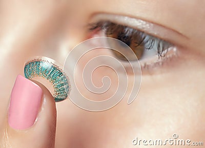 One woman holds a blue contact lens on her finger. Eye care and the choice between the means to improve vision Stock Photo