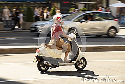 One woman riding a vespa scooter in the city street traffic in motion blur Editorial Stock Photo