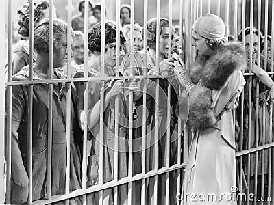 One woman standing in front of a jail talking with a group of women Stock Photo