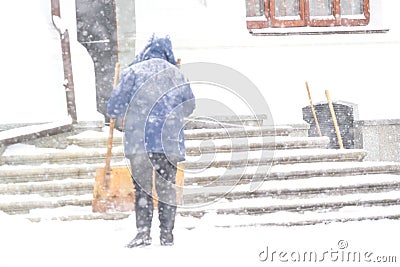 One women shovelling snow in the snowstrom. Cleaning stairs Stock Photo