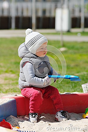 One year old baby boy toddler at playground sandbox Stock Photo