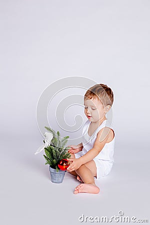 One year old baby tries to decorate the Christmas tree with a Christmas toy Stock Photo