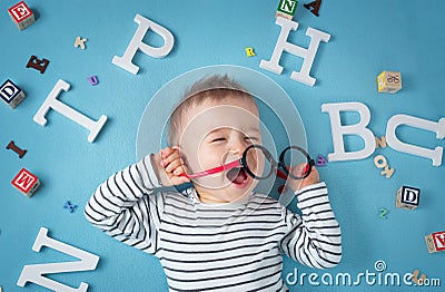 One year old child lying with spectacles and letters Stock Photo