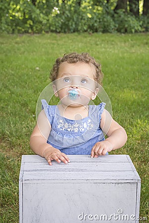 One year old girl sucking on a pacifier Stock Photo