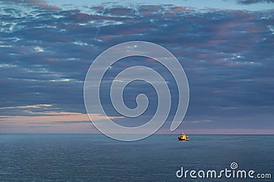 One yellow ship in the open Baltic Sea. sunset in the clouds. Latvian Stock Photo