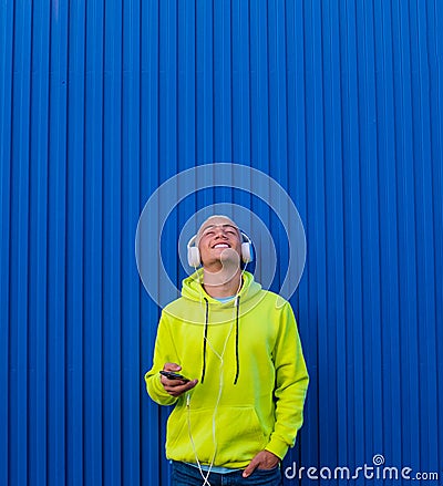 One young man or teenager millennial listening music with his phone and headphones looking up enjoying music and the moment - Stock Photo
