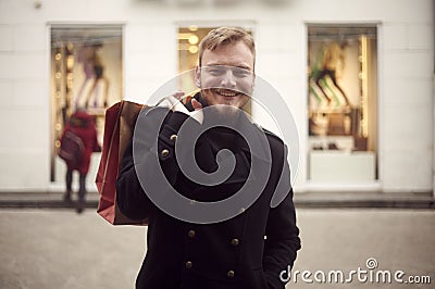 One young man, 20-29 years, looking to camera in front, upper body shot. Smiling holding shopping bag on his back Stock Photo