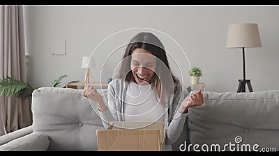 Ongelofelijke jonge vrouw die een kartonnen doos opent met internetwinkelbestelling stock videobeelden Ongelofelijke jonge vrouw die een kartonnen doos opent met internetwinkelbestelling stock videobeelden