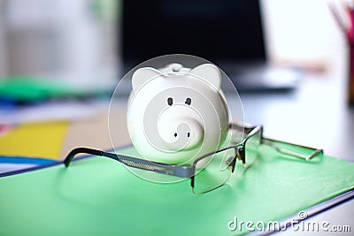 Online banking and investment concept with a pink ceramic piggy bank standing over a white and aluminium computer Stock Photo