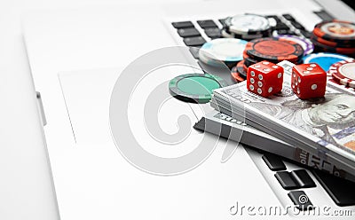 Online casino laptop. Laptop keyboard and chips with dice and money cash dollars on green gaming table. Game addiction gambling Stock Photo