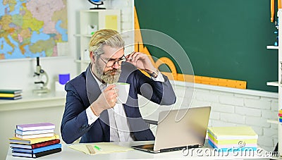 Online course. Senior professor use computer. Computer teacher drink tea at school desk. Bearded man work in computer Stock Photo
