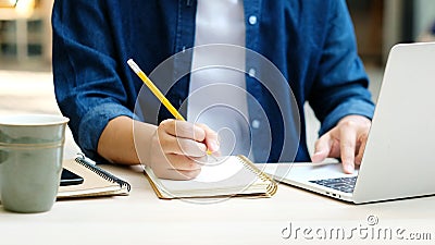 Online education learning, Work from home, Man hand writing on notebook while using laptop computer, Adult male student study Stock Photo