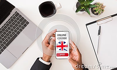 Online English course. Young man holding mobile phone with foreign language application over table, top view Stock Photo