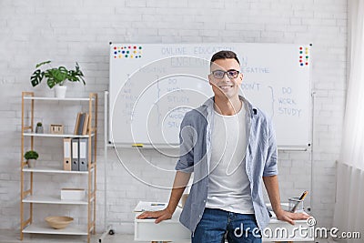 Online English school and modern teacher remotely. Modern smiling tutor with glasses looks at camera and makes videos Stock Photo