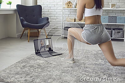 Online fitness at home. The girl does exercises watching the video course the trainer has a laptop at home. Stock Photo