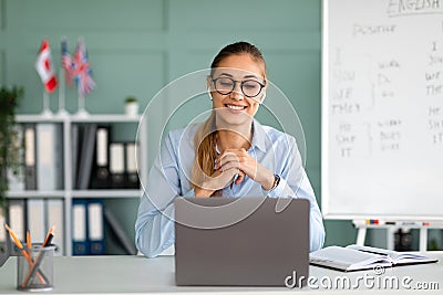 Online foreign languages tutoring. Cheerful female English teacher giving online class, communicating on laptop Stock Photo
