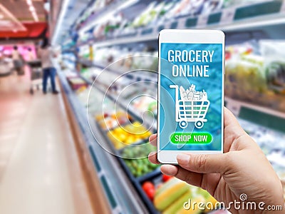 Online grocery shopping concept: Woman hand holding smart phone for ordering food onscreen with icon media on supermarket Stock Photo