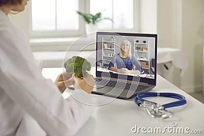 Doctor video calling senior client and telling her about benefits of healthy diet Stock Photo