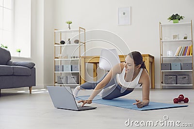 Online home fitness. Woman with laptop training to web video tutorial. Personal trainer giving yoga class via internet Stock Photo