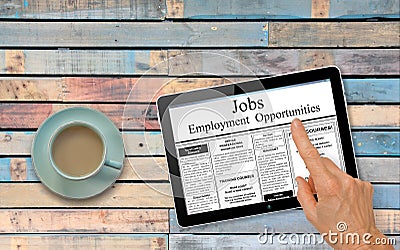 Online job hunting Hand with computer tablet reading employment ads on table with coffee Stock Photo