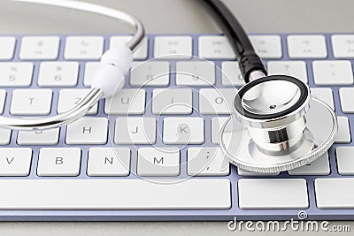 Online modern medicine or pharmacy concept. Stethoscope head on violet white keyboard on grey background Stock Photo